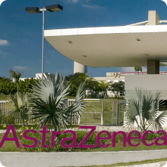 Fachada de unidade da AstraZeneca com logotipo da empresa em área externa e paisagismo ao redor